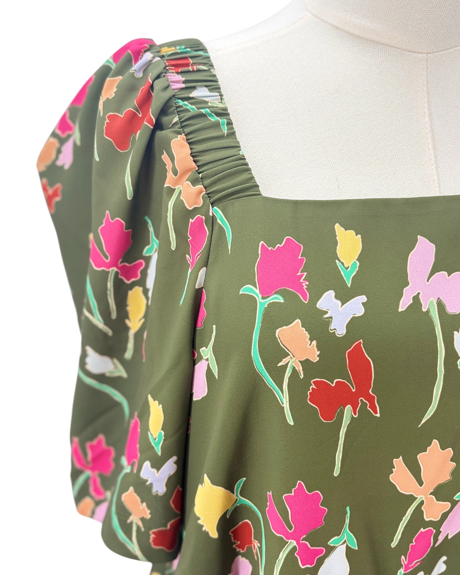 Green dress with floral pattern on a mannequin against a white background