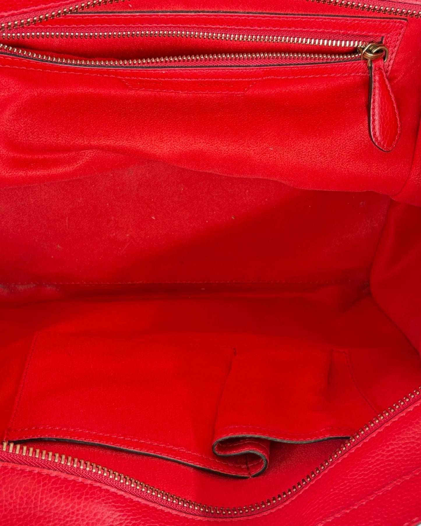 Close-up of a red leather bag with gold zipper
