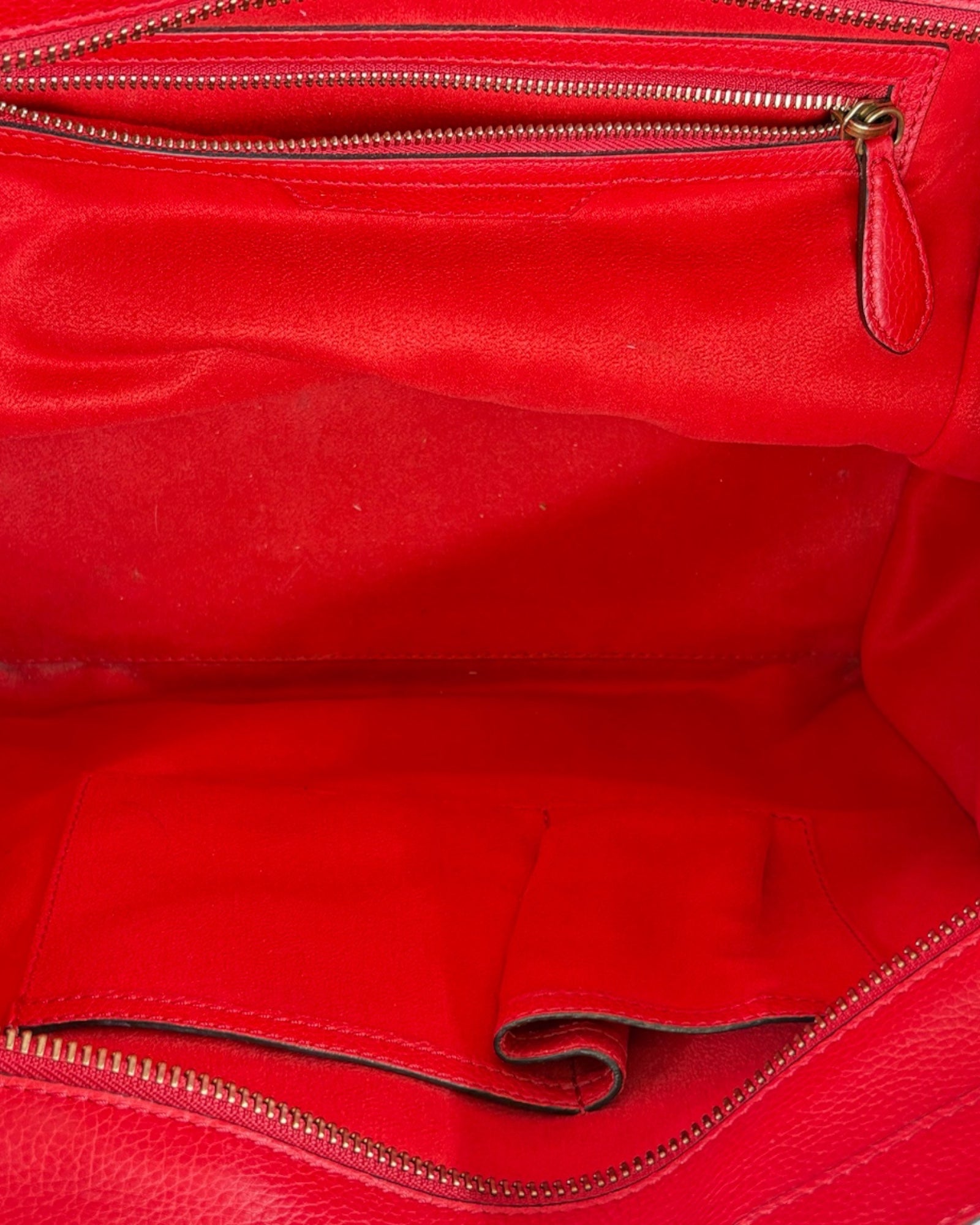 Close-up of a red leather bag with gold zipper