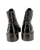 Black leather boots with detailed sole design on a white background