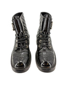 Pair of black leather boots with Chanel logo on a white background