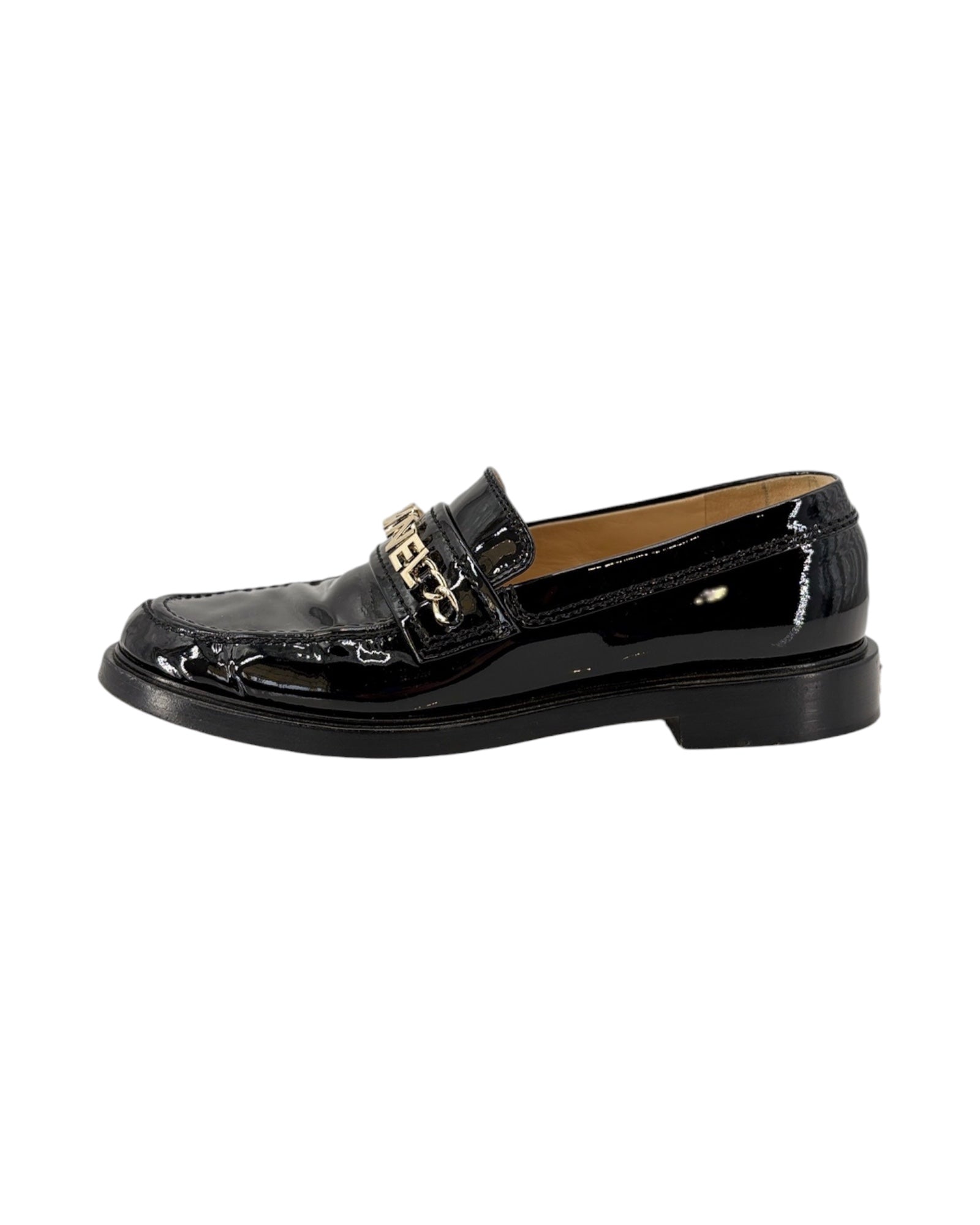 Chanel black patent leather loafer with gold chain detail on a white background