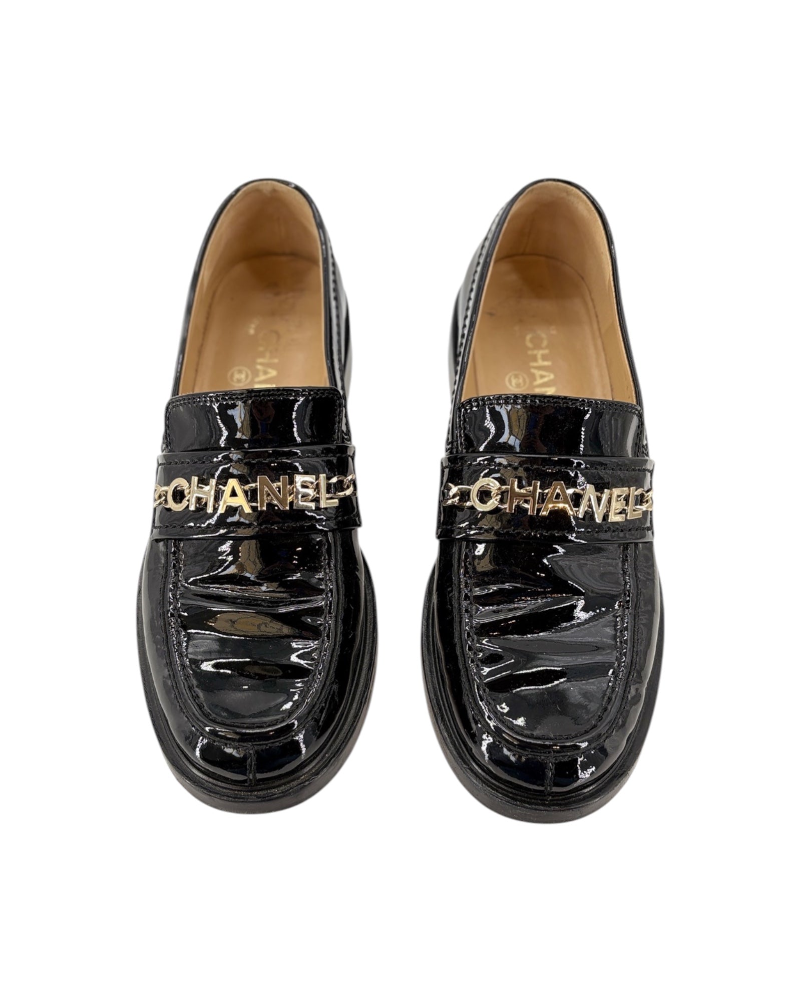 Chanel black patent leather loafer with gold chain detail on a white background