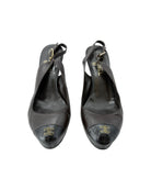 Pair of black leather shoes with Chanel logo on a white background