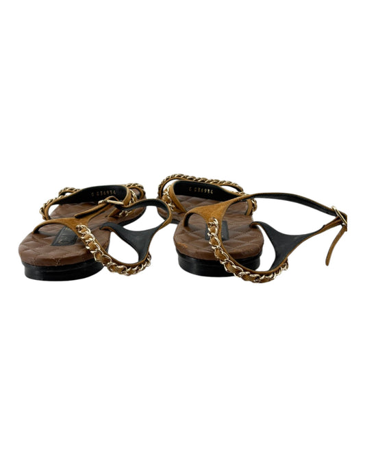 Pair of sandals with gold chains on a white background