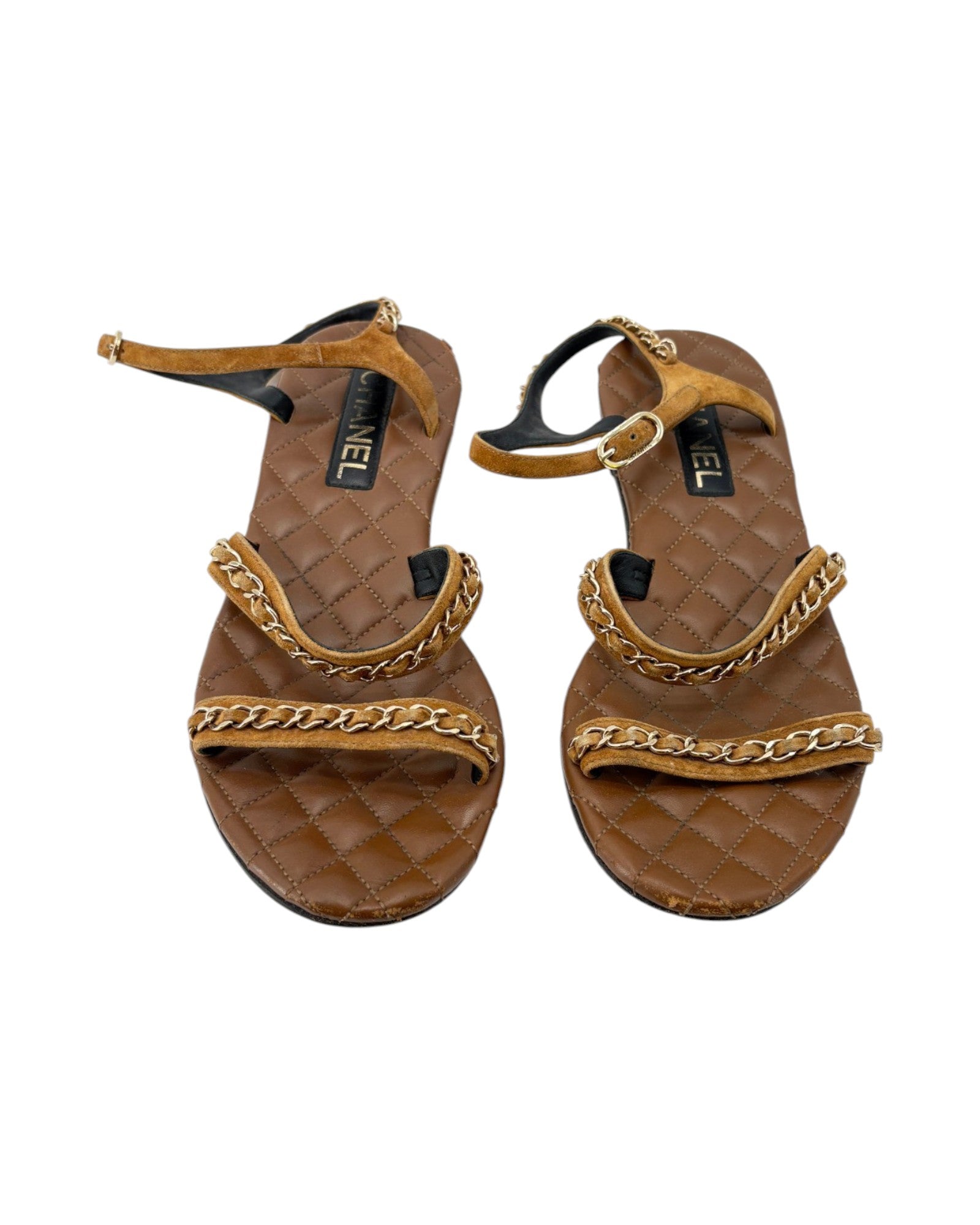Pair of brown sandals with gold chain details on a white background