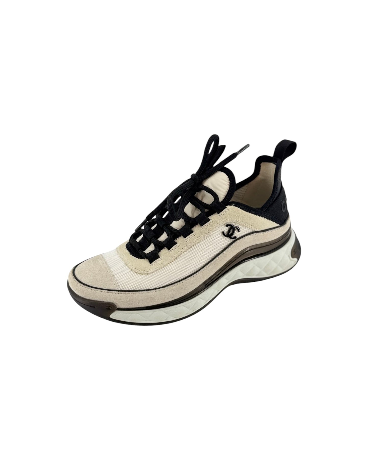 A Chanel low-top sneaker featuring a cream and beige mesh upper, black laces, a black heel tab, and a chunky beige and black sole with the iconic interlocking CC logo on the side.