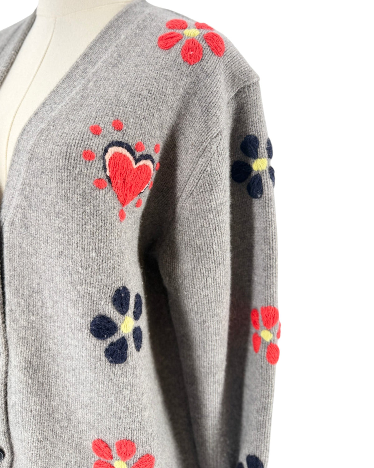 Grey button front cardigan with red floral and heart embroidery on a mannequin with a white background