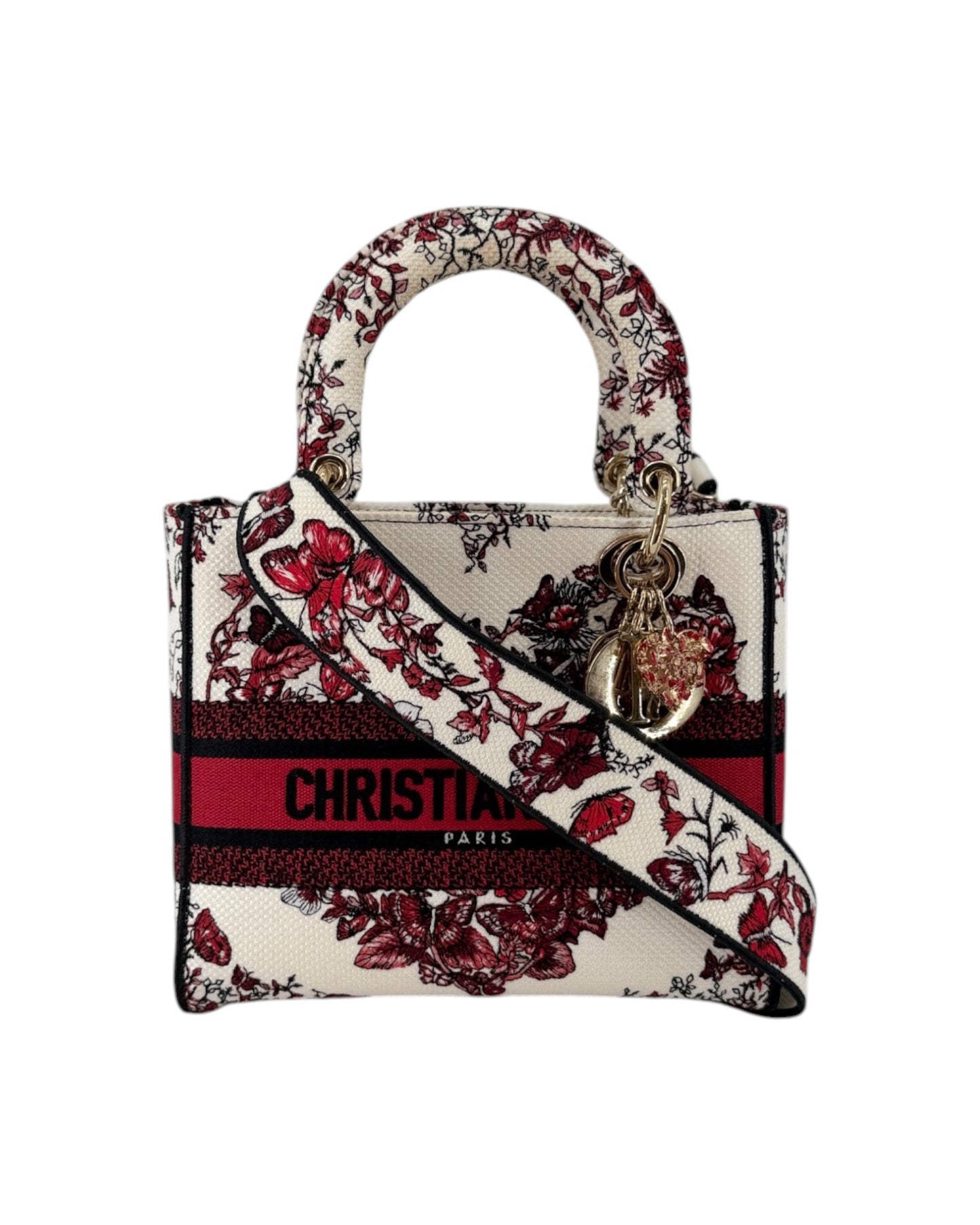 Christian Dior Lady Dior handbag featuring a cream canvas base with a red and burgundy floral pattern, a red stripe with black lettering, and a gold-tone CD charm.
