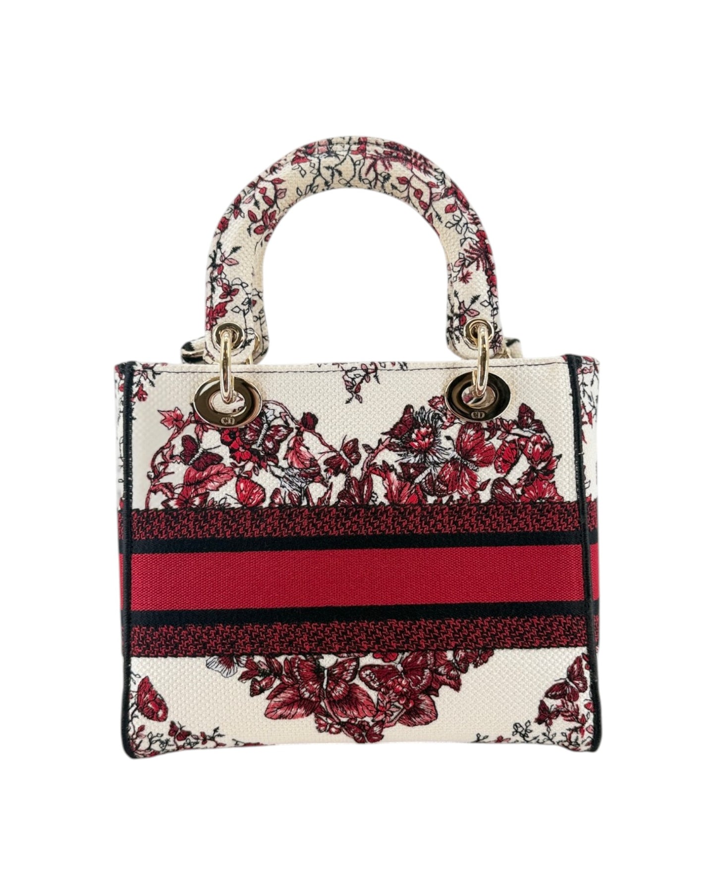 A structured handbag with a cream base, featuring a red and black floral pattern, a bold red horizontal stripe with black borders, and a matching top handle, shown against a plain white background.