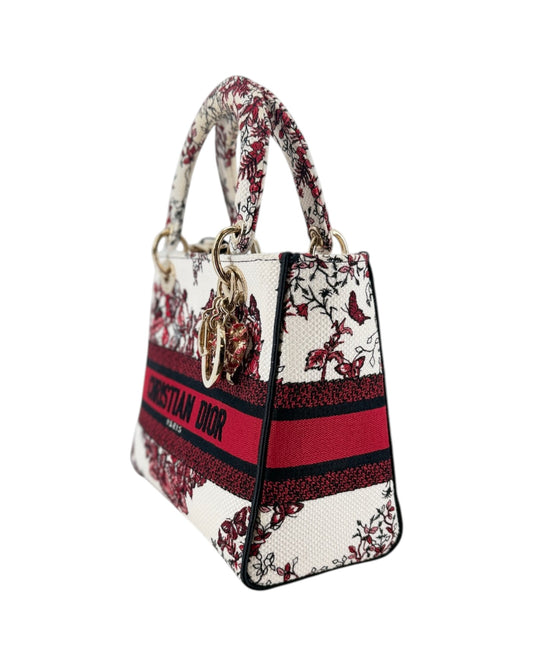 A Christian Dior Lady Dior handbag featuring a red and black floral pattern on a white background, with a signature red and black web stripe across the front and gold-tone hardware.