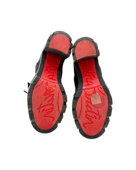 Red soles of black shoes with visible wear on a white background