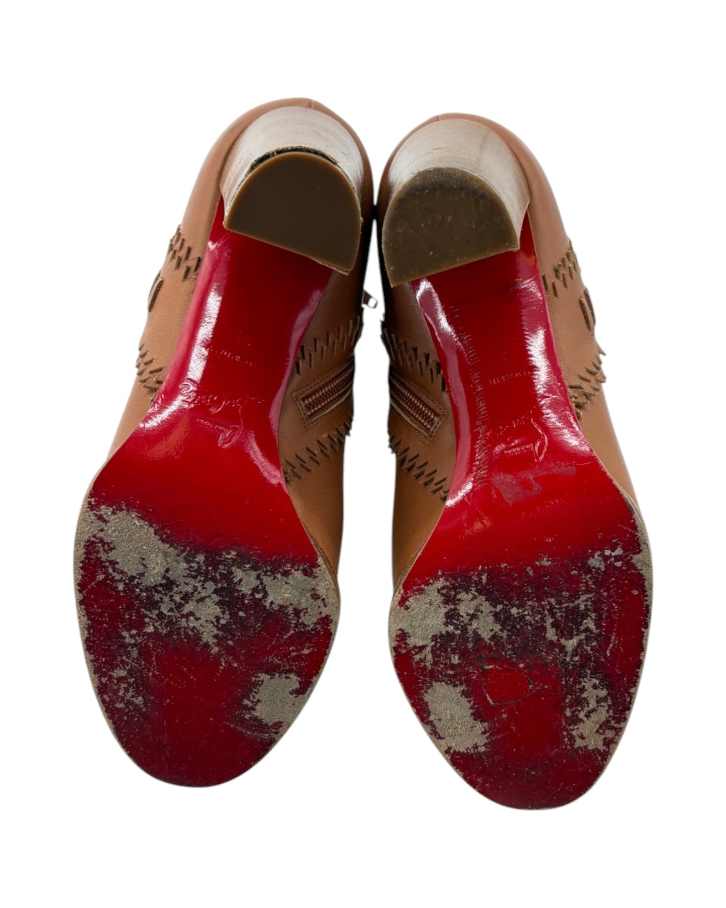 Pair of worn shoes with red soles on a white background