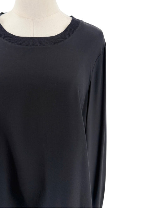 A close-up of a black long-sleeve top displayed on a cream dress form against a white background.