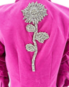 Pink blazer with a decorative silver flower on the back against a white background