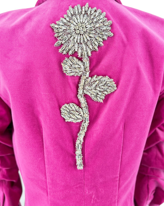 Pink blazer with a decorative silver flower on the back against a white background
