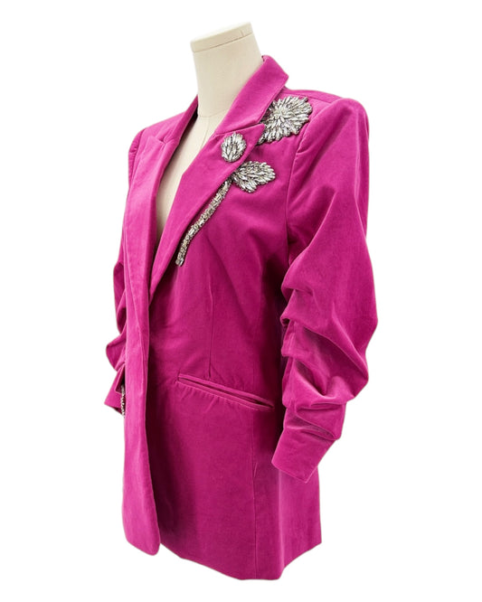 Pink blazer with embellishments on a mannequin against a white background