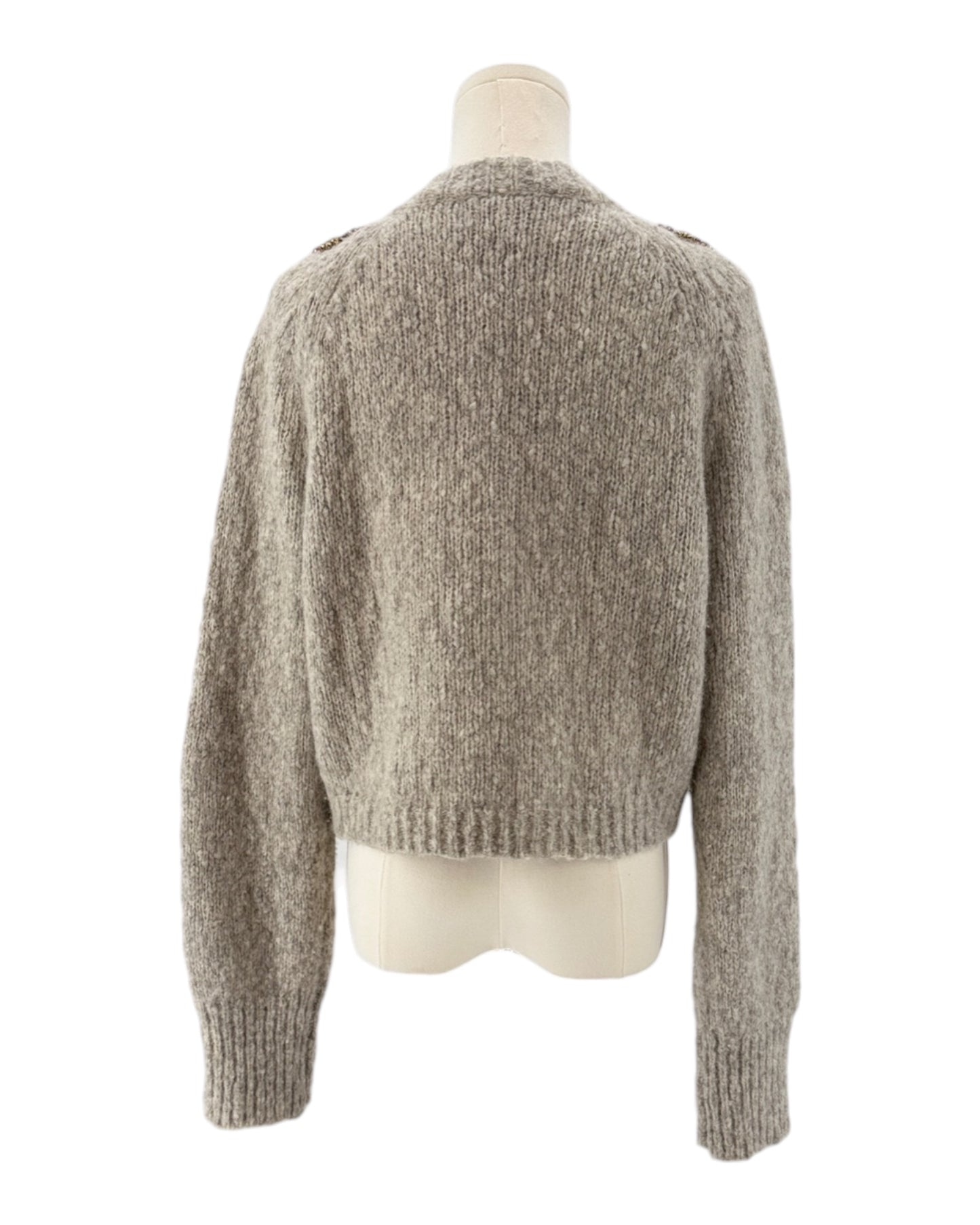 Knitted cardigan with floral embellishments on a mannequin against a white background