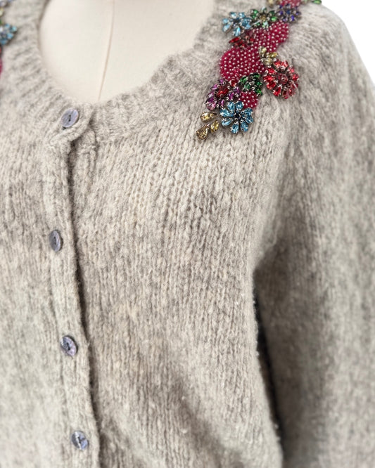 Knitted cardigan with floral embellishments on a mannequin against a white background
