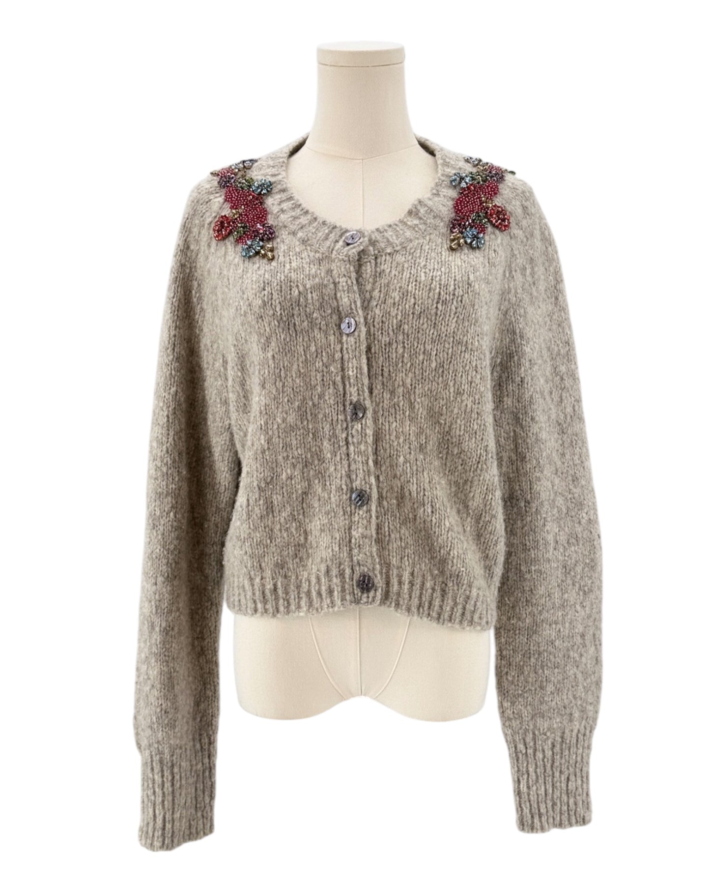 Knitted cardigan with floral embellishments on a mannequin against a white background