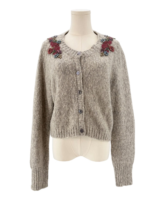 Knitted cardigan with floral embellishments on a mannequin against a white background