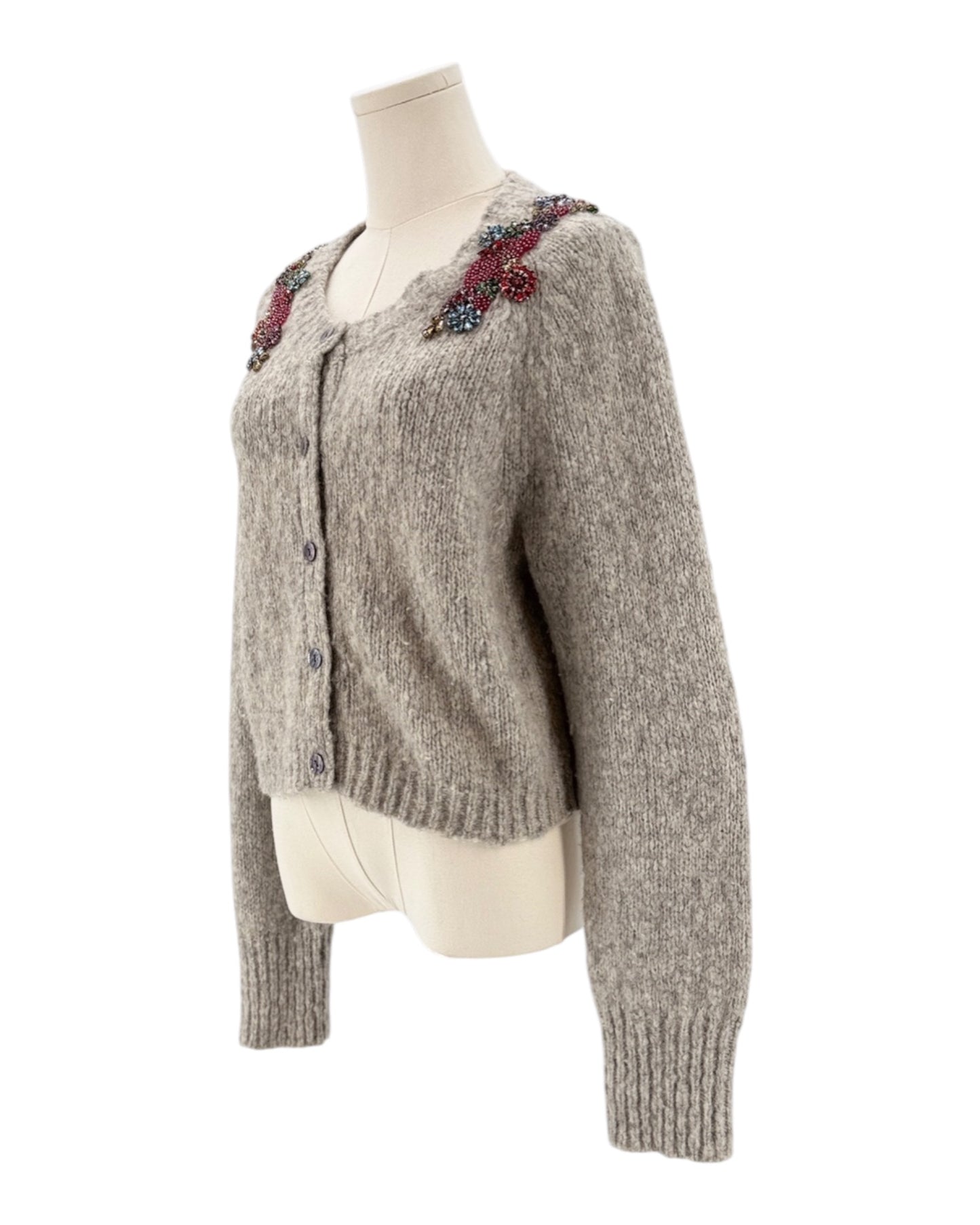 Knitted cardigan with floral embellishments on a mannequin against a white background