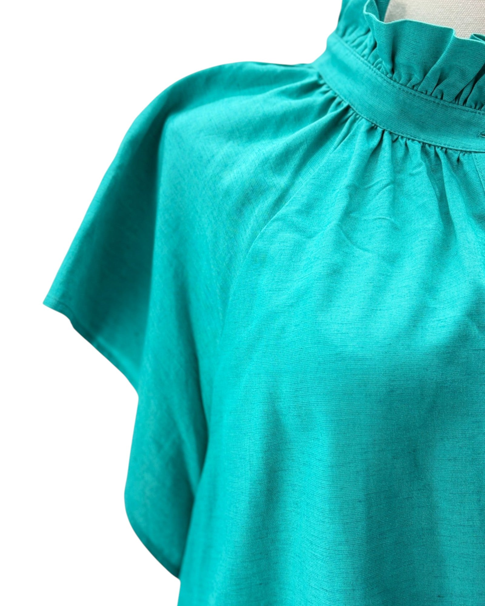 Close-up of a teal blouse with a white background