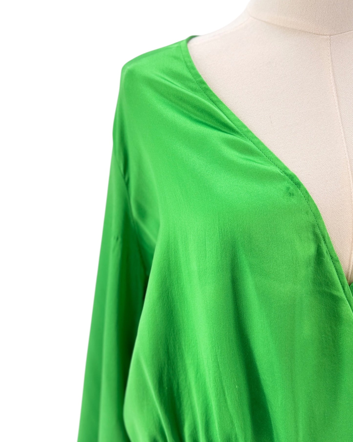 Green fabric draped over a mannequin on a white background