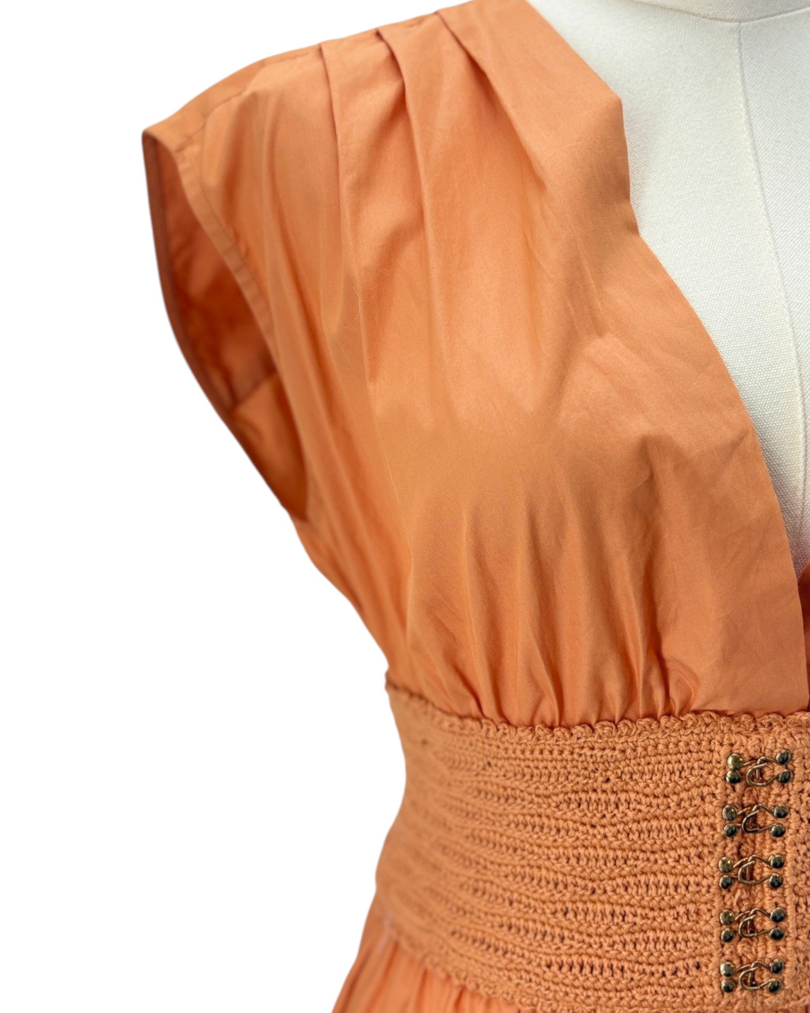 Orange dress with a textured skirt on a mannequin against a white background