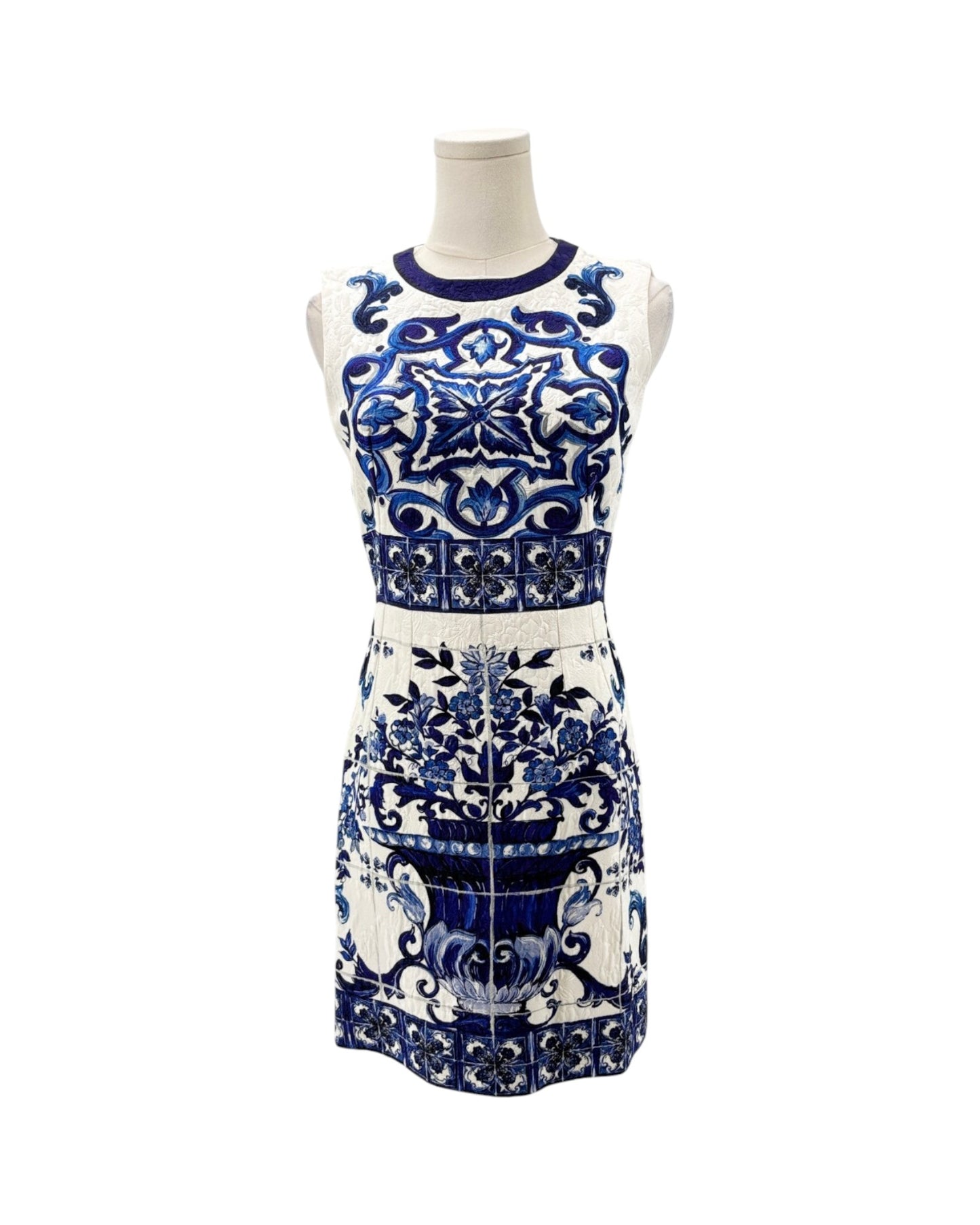 A sleeveless white knit dress with a blue and navy floral and geometric pattern, displayed on a white mannequin torso against a white background.