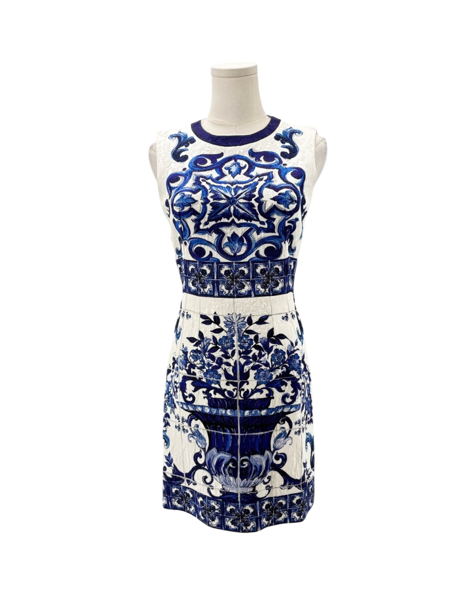 A sleeveless white knit dress with a blue and navy floral and geometric pattern, displayed on a white mannequin torso against a white background.