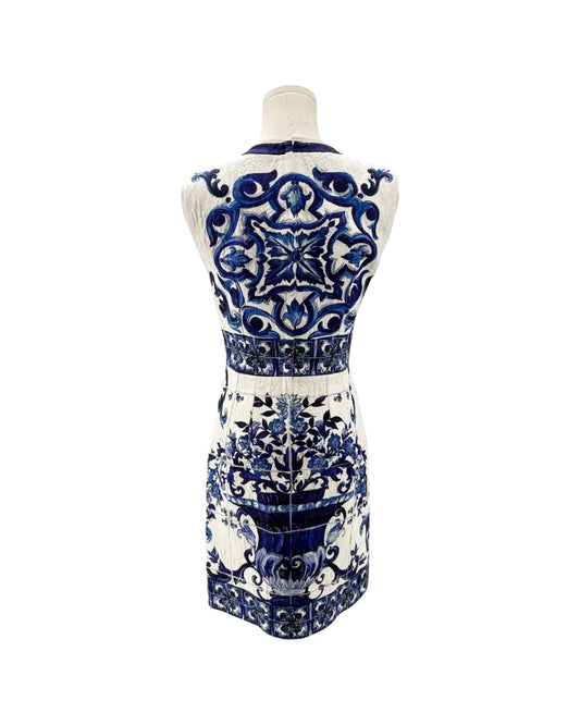 A sleeveless white dress with an intricate blue and black baroque-style pattern, shown from the back on a mannequin against a white background.