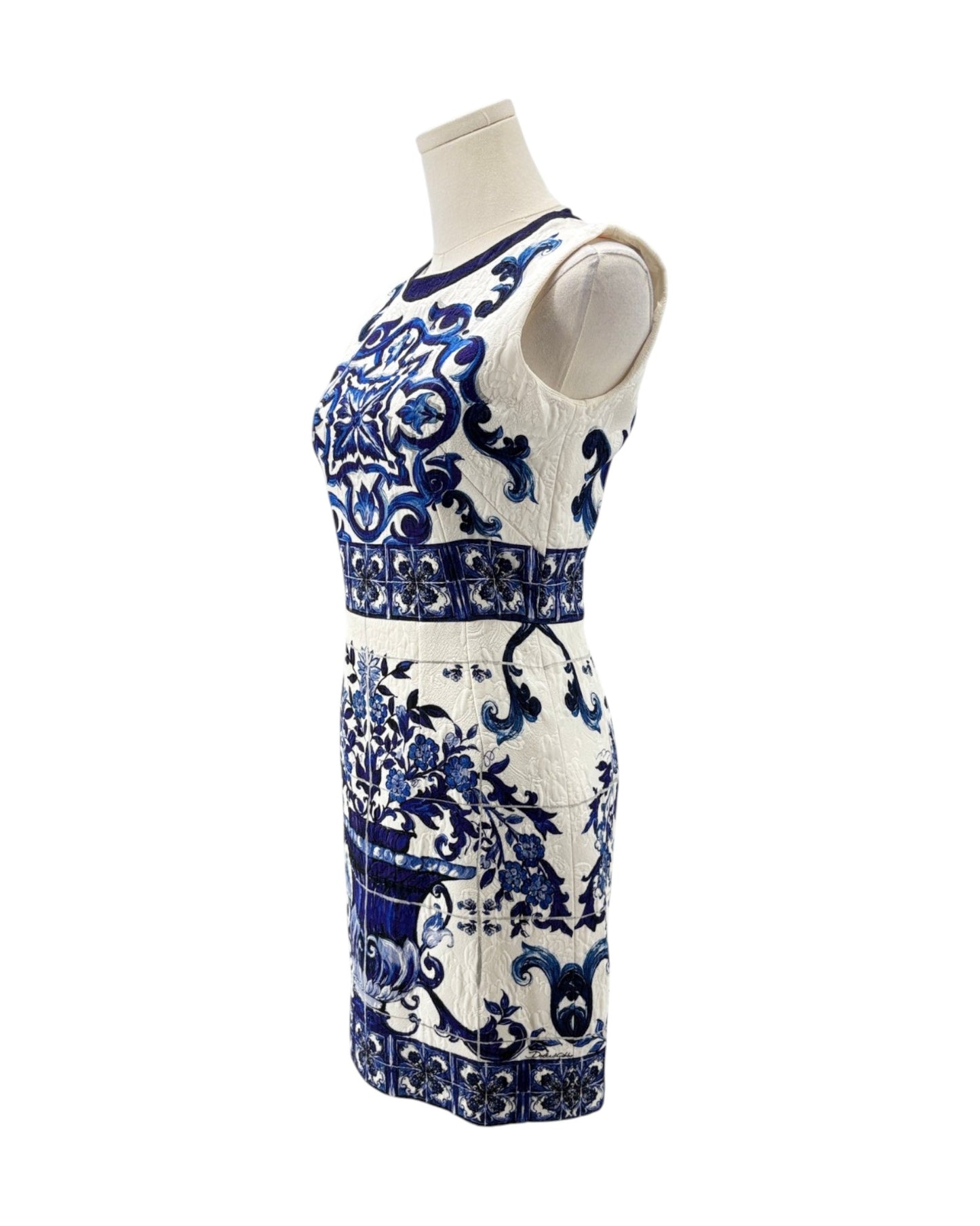 A sleeveless white knit dress with a blue floral and scroll pattern, displayed on a mannequin torso against a plain white background.