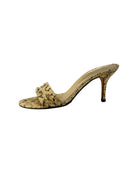 Gold high-heeled shoes with snake print pattern on a white background