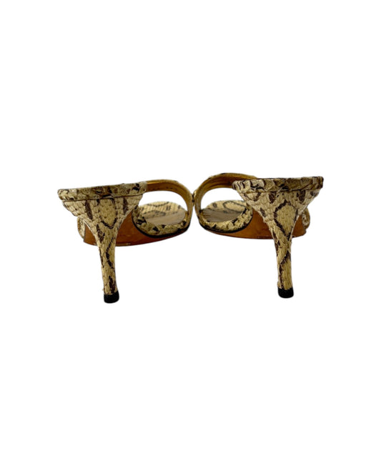 Gold high-heeled shoes with snake print pattern on a white background