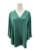Green blouse on a mannequin against a white background