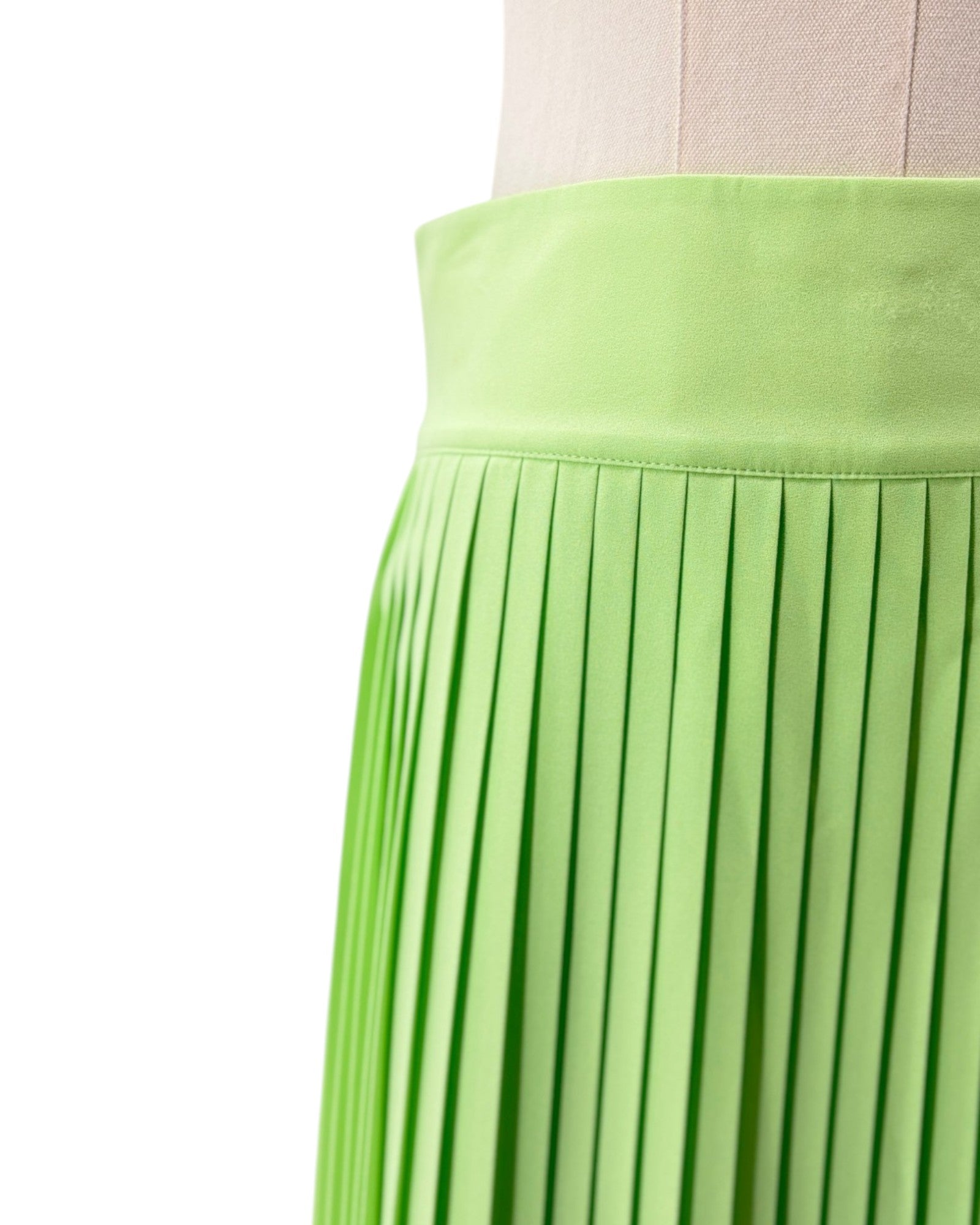 Green pleated skirt on a mannequin against a white background