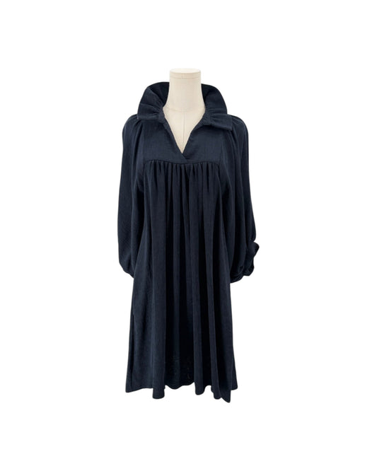 High ruffle stand-up collar, notched v-neck, gathered detailing at the bodice, voluminous loose blouson sleeves, shift silhouette, side pockets on a mannequin on a white background