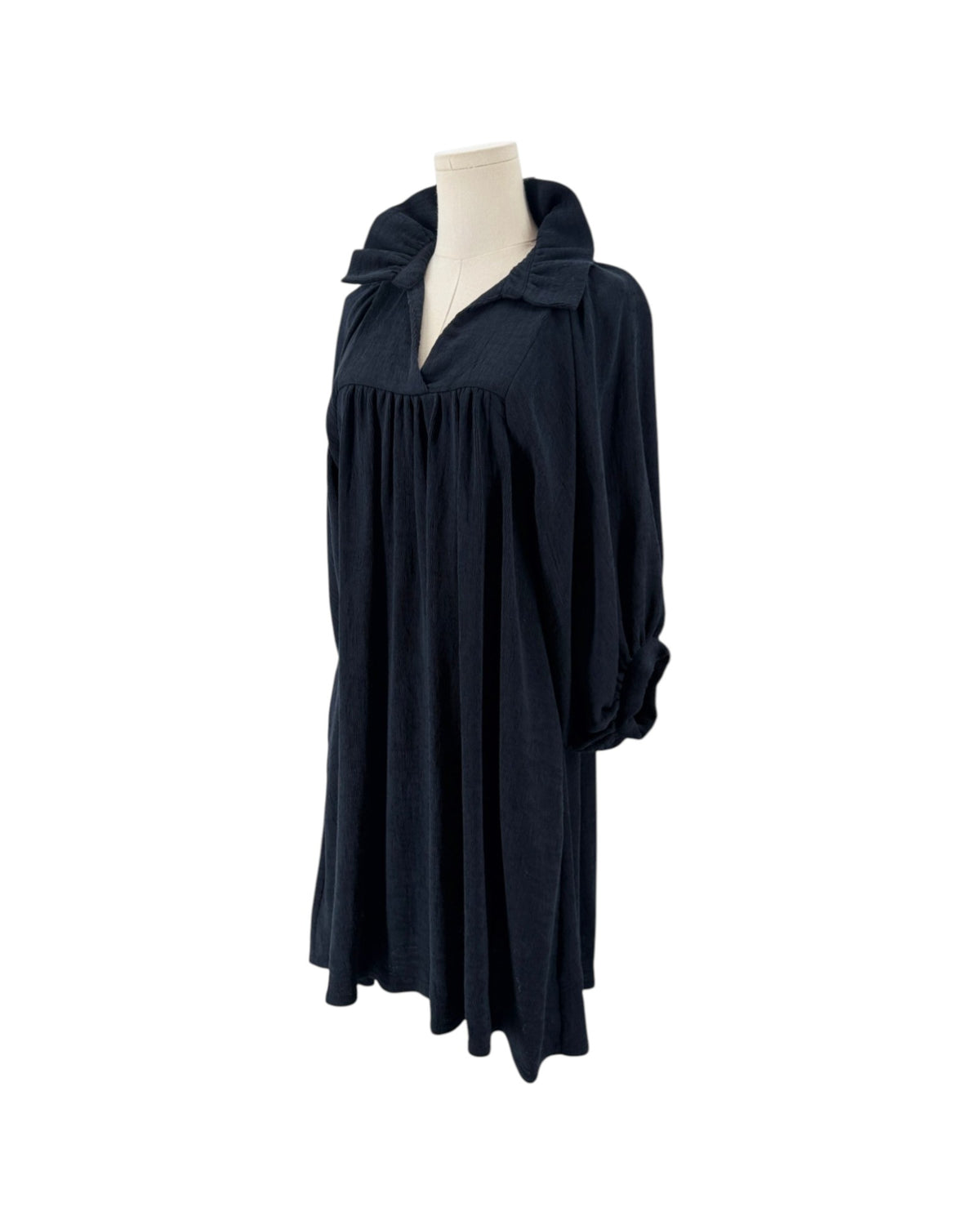 High ruffle stand-up collar, notched v-neck, gathered detailing at the bodice, voluminous loose blouson sleeves, shift silhouette, side pockets on a mannequin on a white background