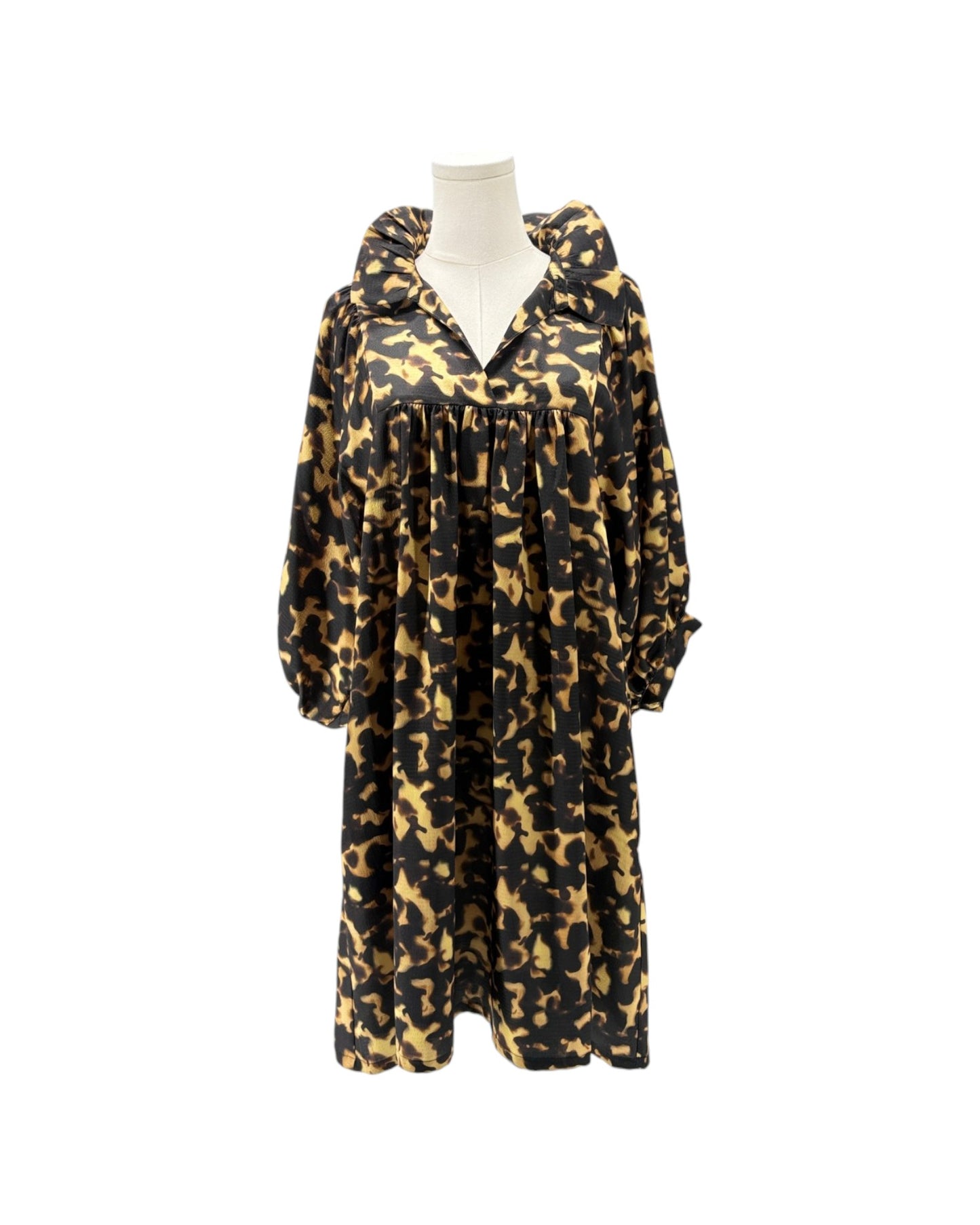 A long-sleeved hooded dress with a black and tan camouflage pattern, displayed on a white mannequin torso against a plain white background.
