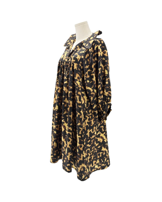 A long-sleeve, loose-fitting tunic dress with a black and tan leopard print pattern, displayed on a mannequin torso against a plain white background.
