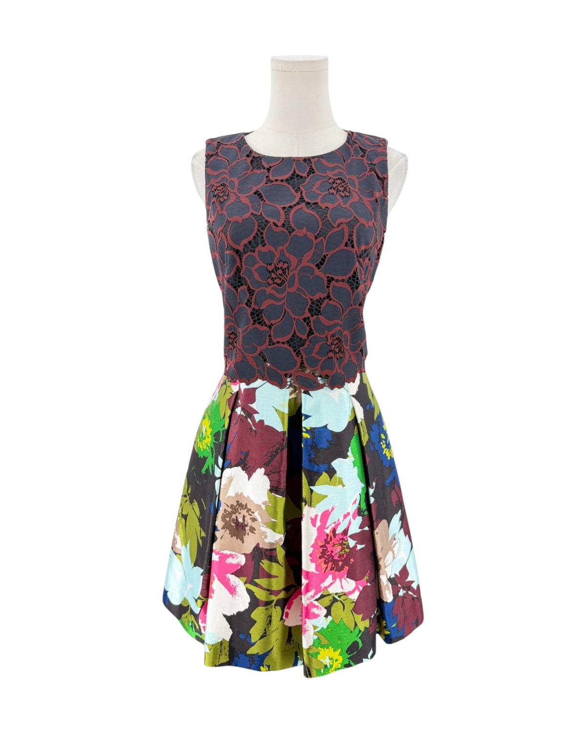 A sleeveless fit-and-flare dress displayed on a mannequin against a white background. The bodice features a dark red and black floral lace overlay, while the flared skirt has a vibrant multicolor floral print with pink, blue, green, and yellow tones.