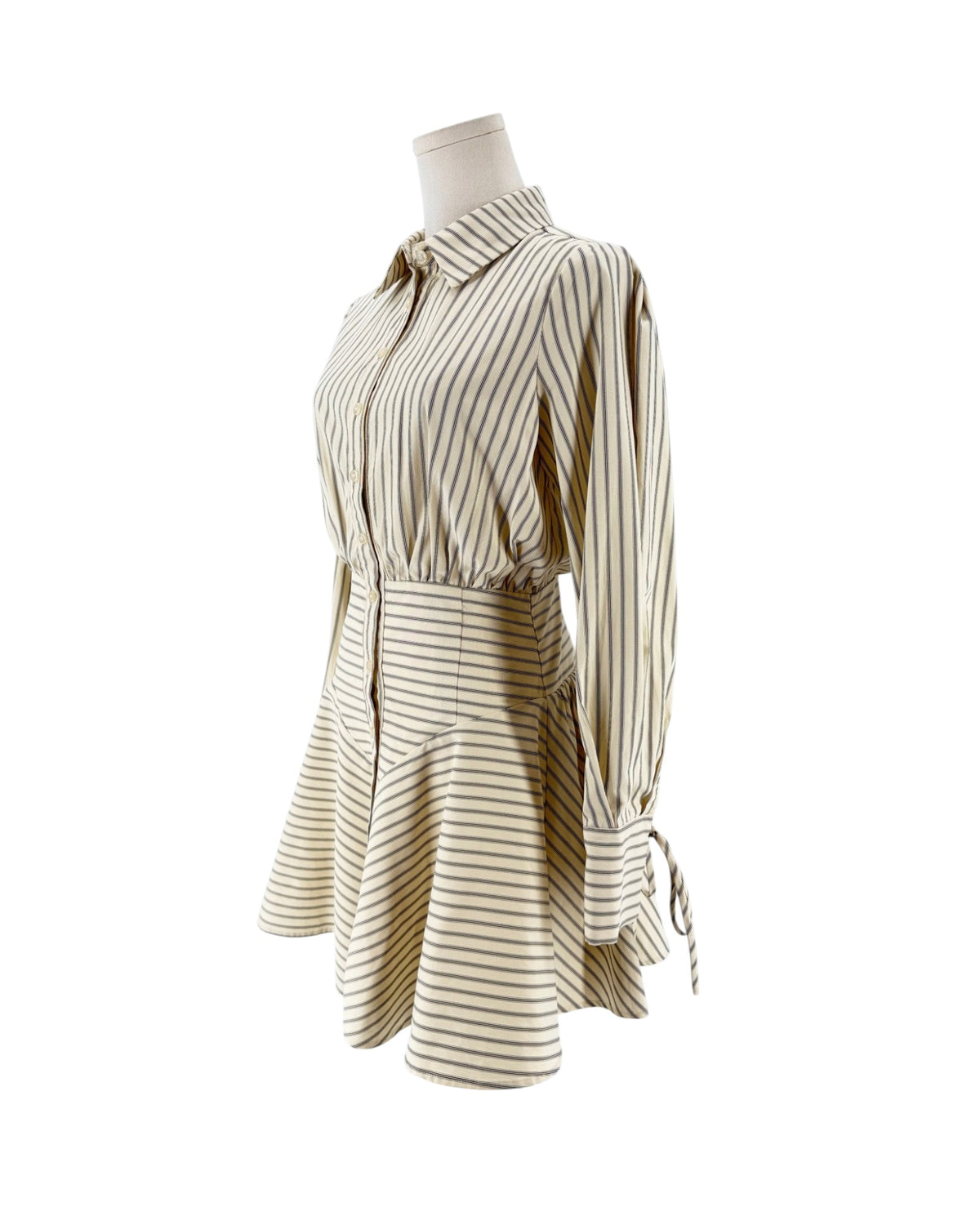 Striped shirt dress, point collar, clean button-front placket closure, distinct smocked and gathered detailing, long sleeves detailed with adjustable drawstring/tie accent at cuffs on a mannequin on a white background