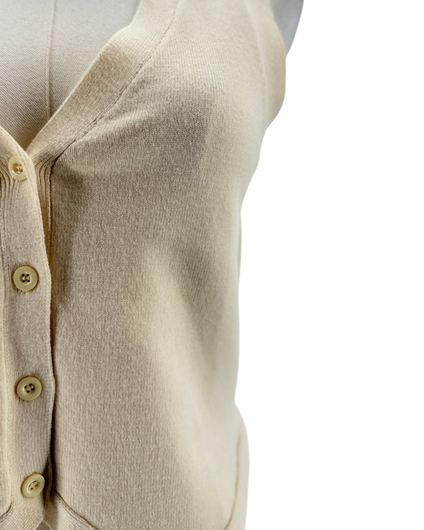 Close-up of a beige cardigan with button details on a white background
