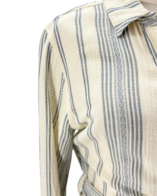 Close-up of a long-sleeve collared shirt with vertical blue-gray stripes on a warm cream base, featuring a subtle woven geometric pattern along the placket.