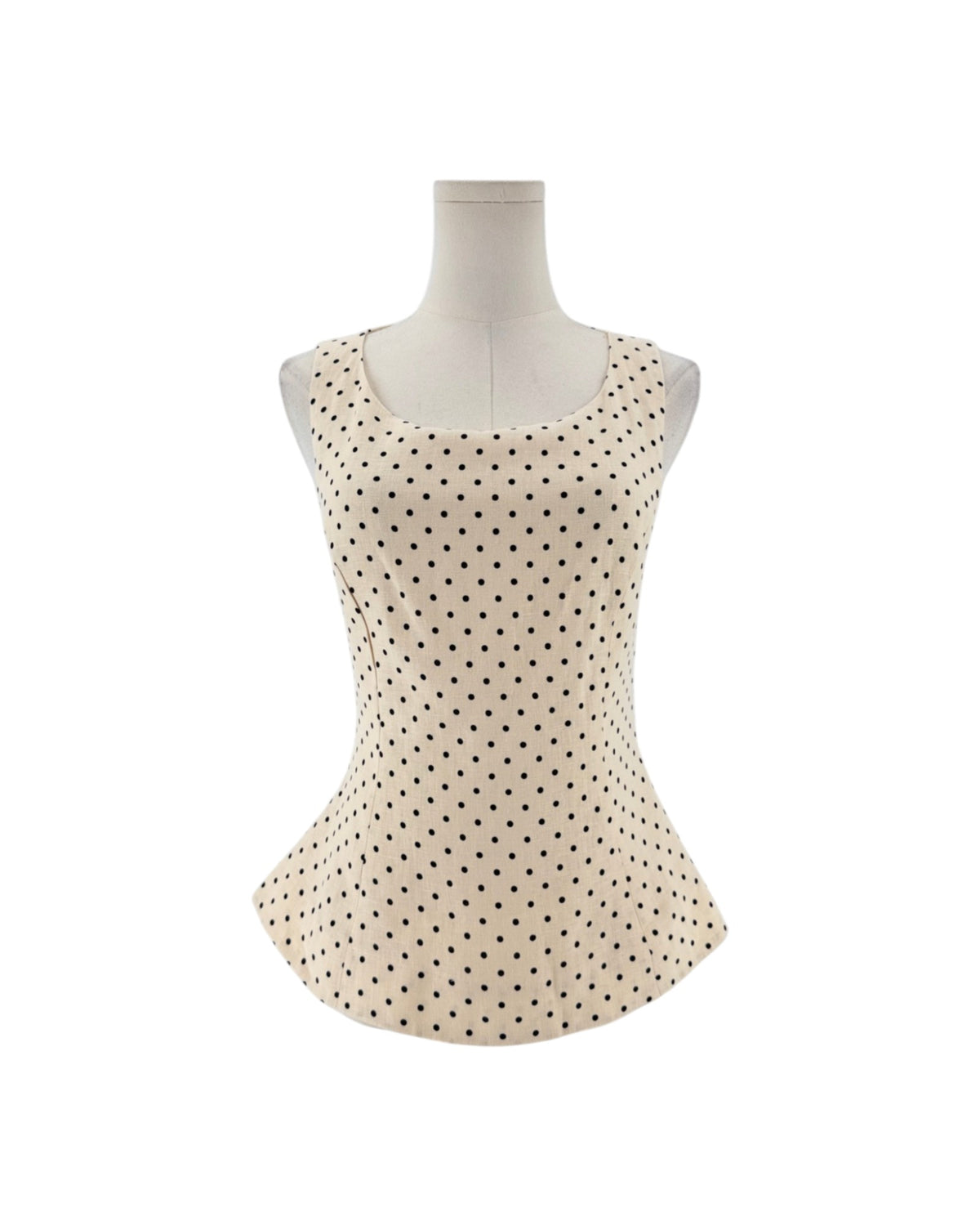 Sleeveless cream peplum top with back polka dots on a mannequin on a white background