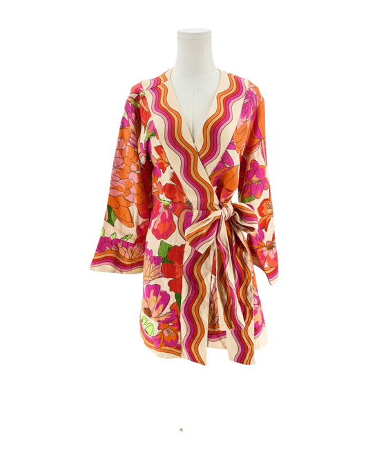 A long-sleeve wrap mini with a tie waist, featuring a vibrant retro floral and wavy stripe pattern in orange, pink, red, and green on a cream background, displayed on a white mannequin torso.