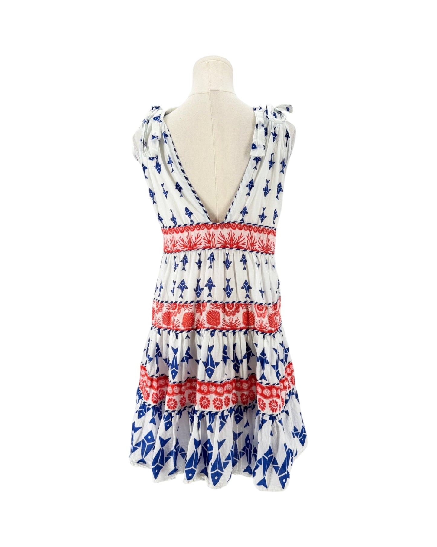 A sleeveless tiered dress displayed on a mannequin torso against a plain white background. The dress has a white base with blue anchor patterns and red horizontal bands with floral motifs.