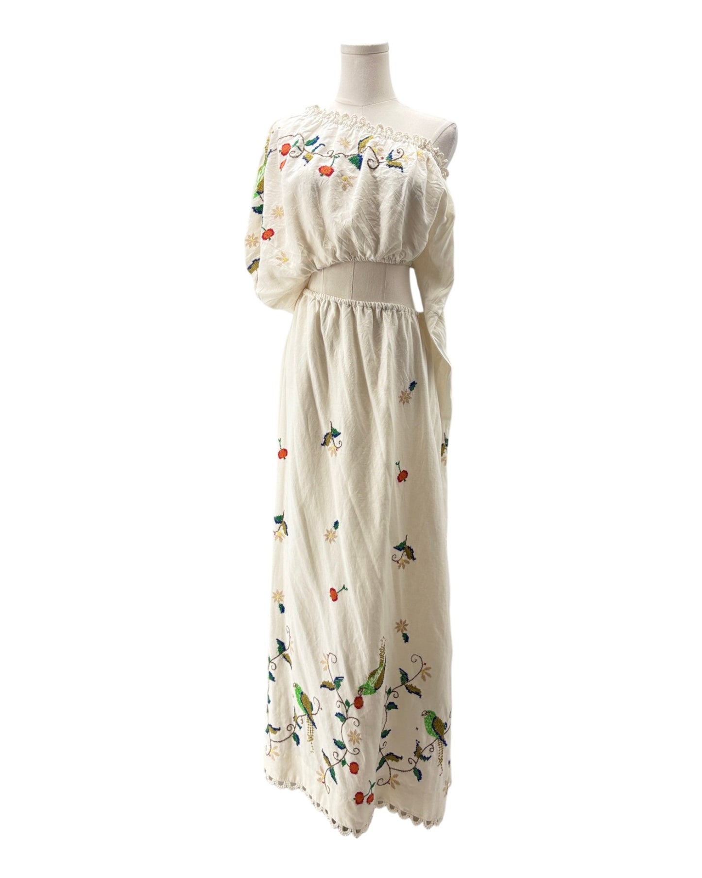 White dress with floral and bird patterns on a mannequin against a white background