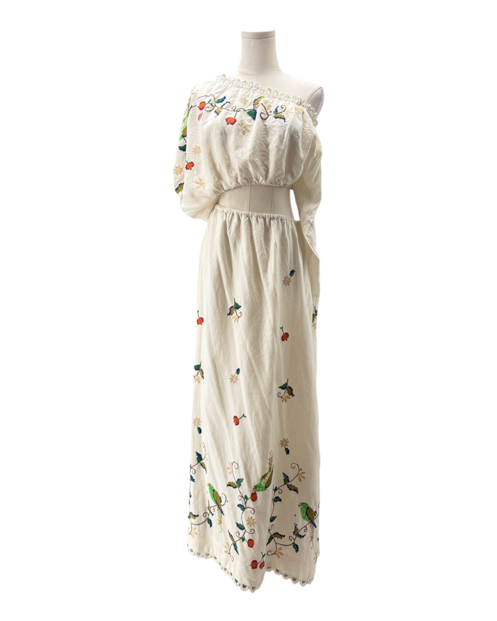 White dress with floral and bird patterns on a mannequin against a white background
